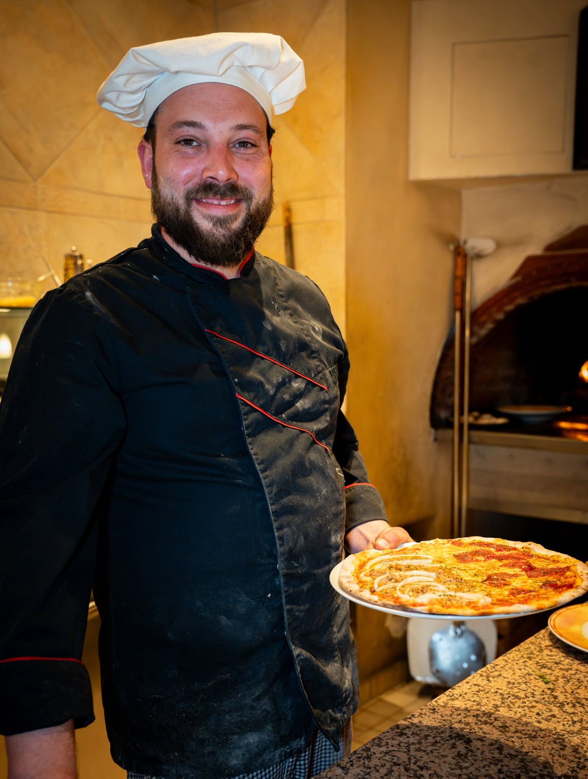 Pizzaiolo mit frisch gebackener Pizza bei La Tavola da Franco